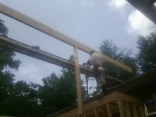 Carpenter setting a ridge beam over a new addition frame — Ice Dam Removal by Roofing Brothers in New Goshen