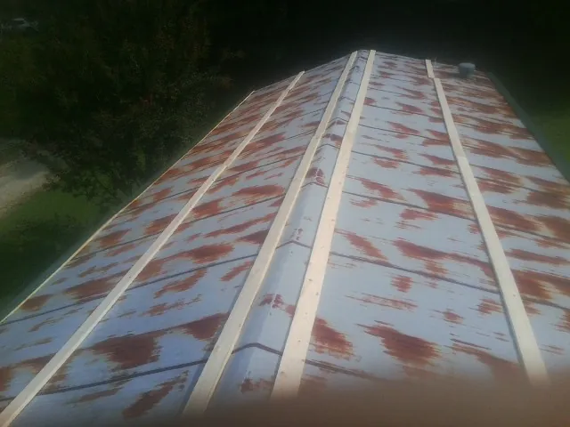 Rusted metal roof panels with new wood purlins before replacement — Storm Damage Roof Repair in New Goshen by Roofing Brothers