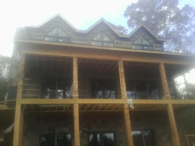 Dormers and porch framing on a large log home under construction — Roof Coating work by our crew in New Goshen