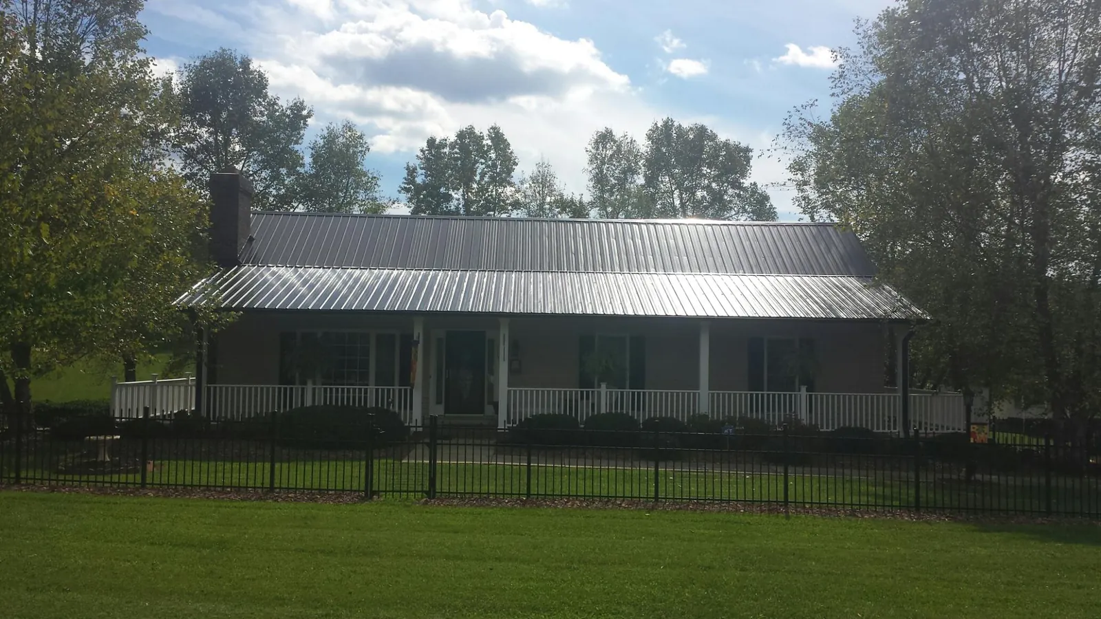 Gray metal roof on a brick ranch with a full width front porch — Gutter Guard Installation work by our crew in New Goshen