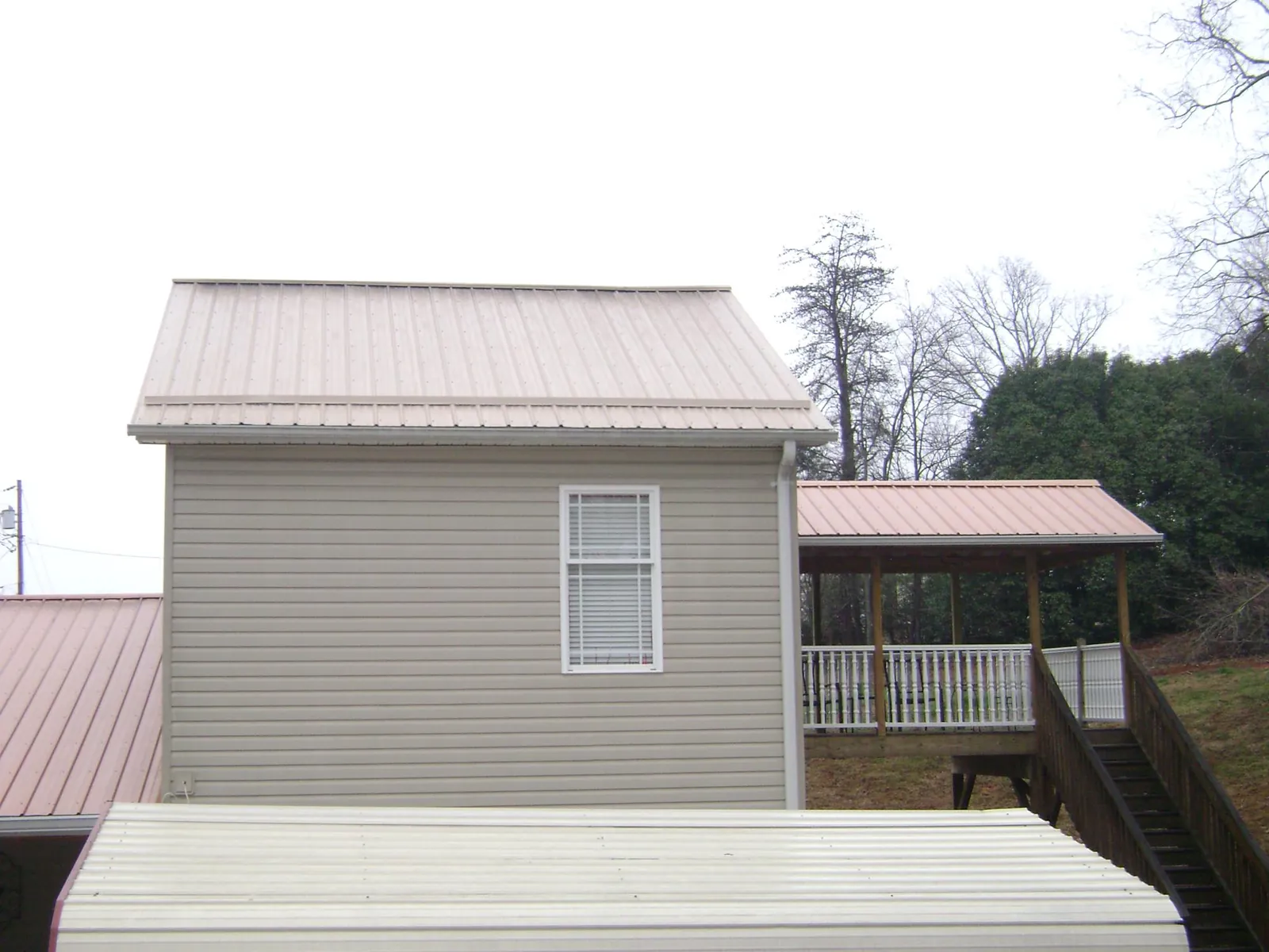 Tan metal roofs on a two story addition and attached porch, from a Roof Replacement job in New Goshen