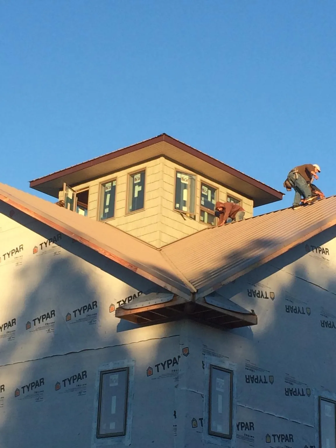 Roofers working around a rooftop cupola on a new metal roof at sunset — Roof Waterproofing in New Goshen by Roofing Brothers